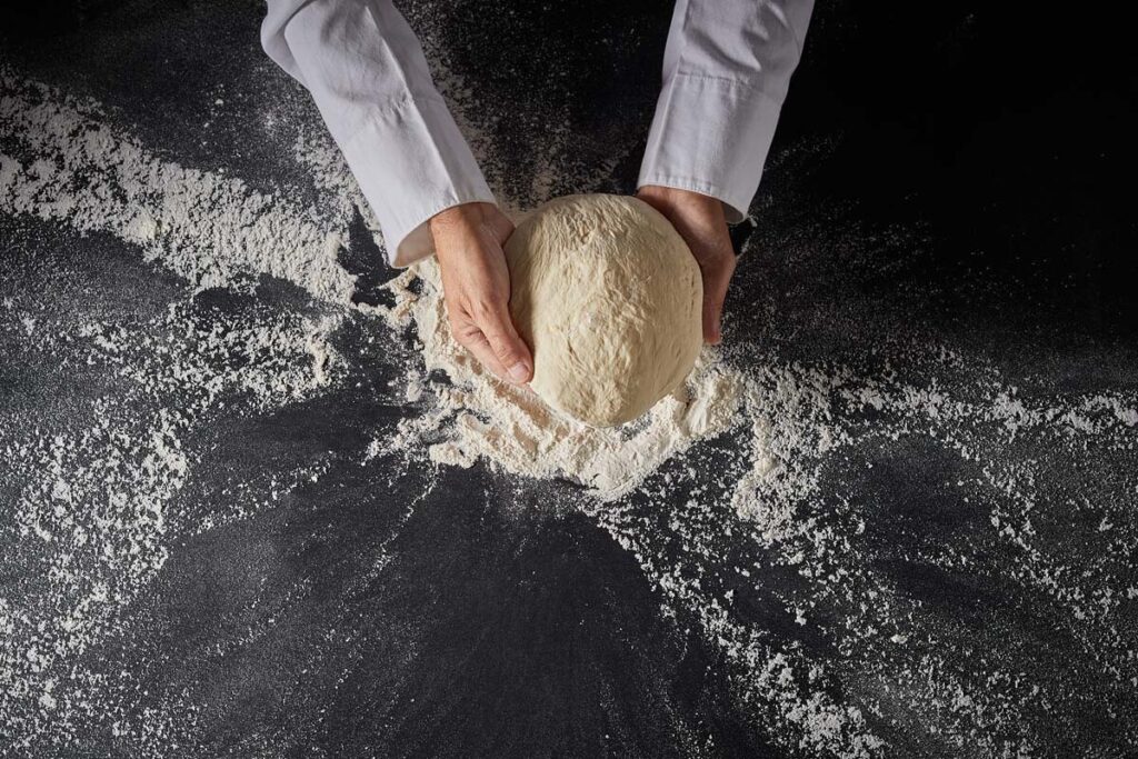 Preparing raw pizza dough with tons of flour