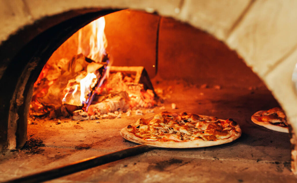 Italian pizza cooking in a wood fired pizzeria oven