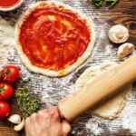 Fresh original Italian perfect pizza preparation, close-up of hands in action