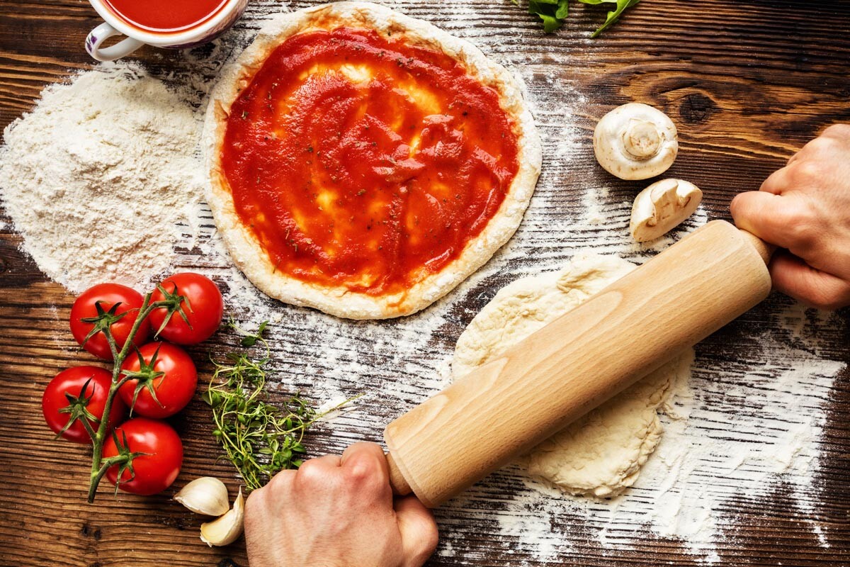 Fresh original Italian perfect pizza preparation, close-up of hands in action