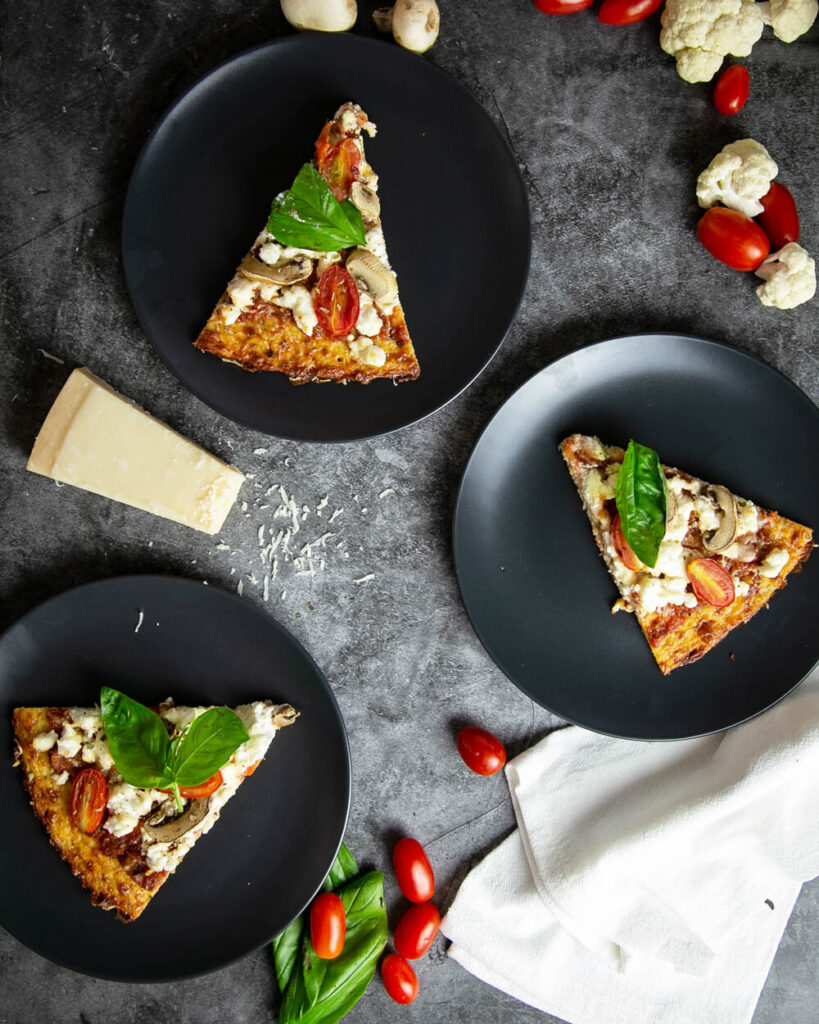 3 slices of cauliflower crust pizza on black plates