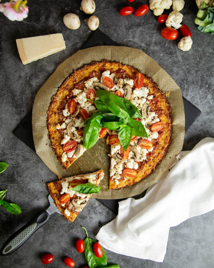 Taking a slice of cauliflower crust pizza with a marble background