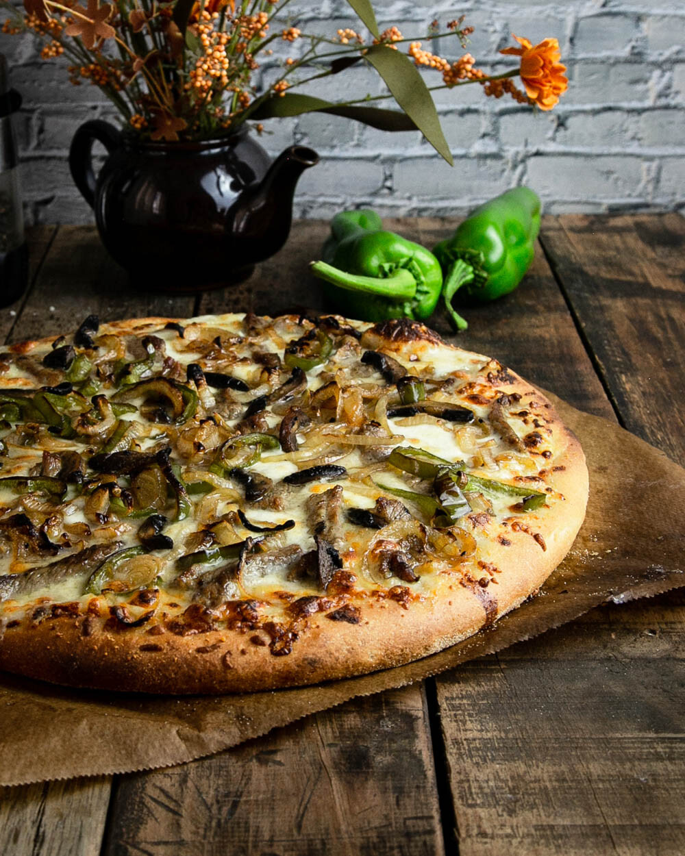 Philly cheesesteak pizza on a dark wood background