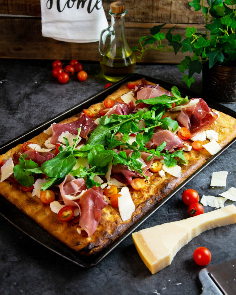 Pizza Al Taglio topped with fresh tomatoes prosciutto and basil