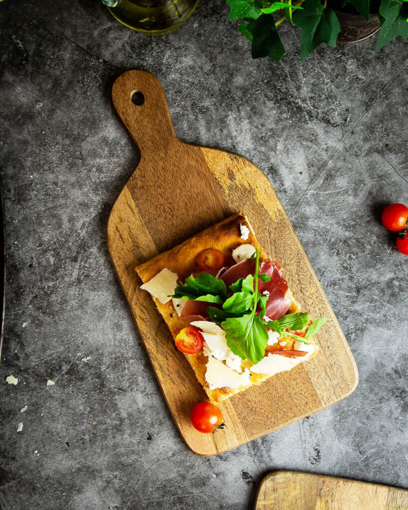 A slice of pizza al taglio on a wooden board