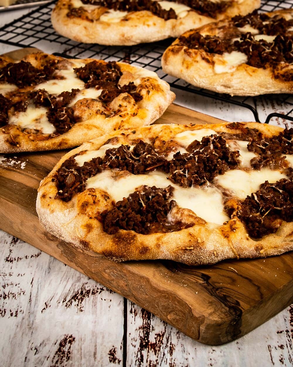 Side view of Roman pinsa pizzas with bolognese on a cutting board