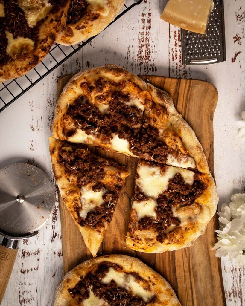 Top view of sliced Roman pinsa pizza with bolognese