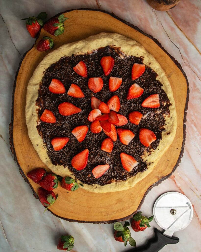 Brazilian sweet pizza with chocolate and strawberries on and wood background