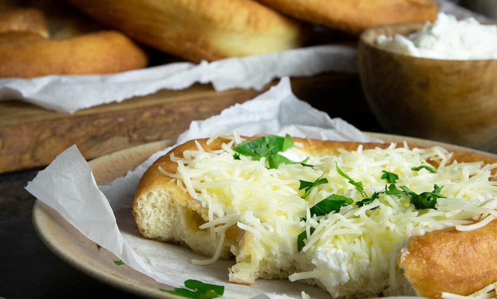 Half eaten Langos topped with the Hungarian traditional sour cream and cheese.