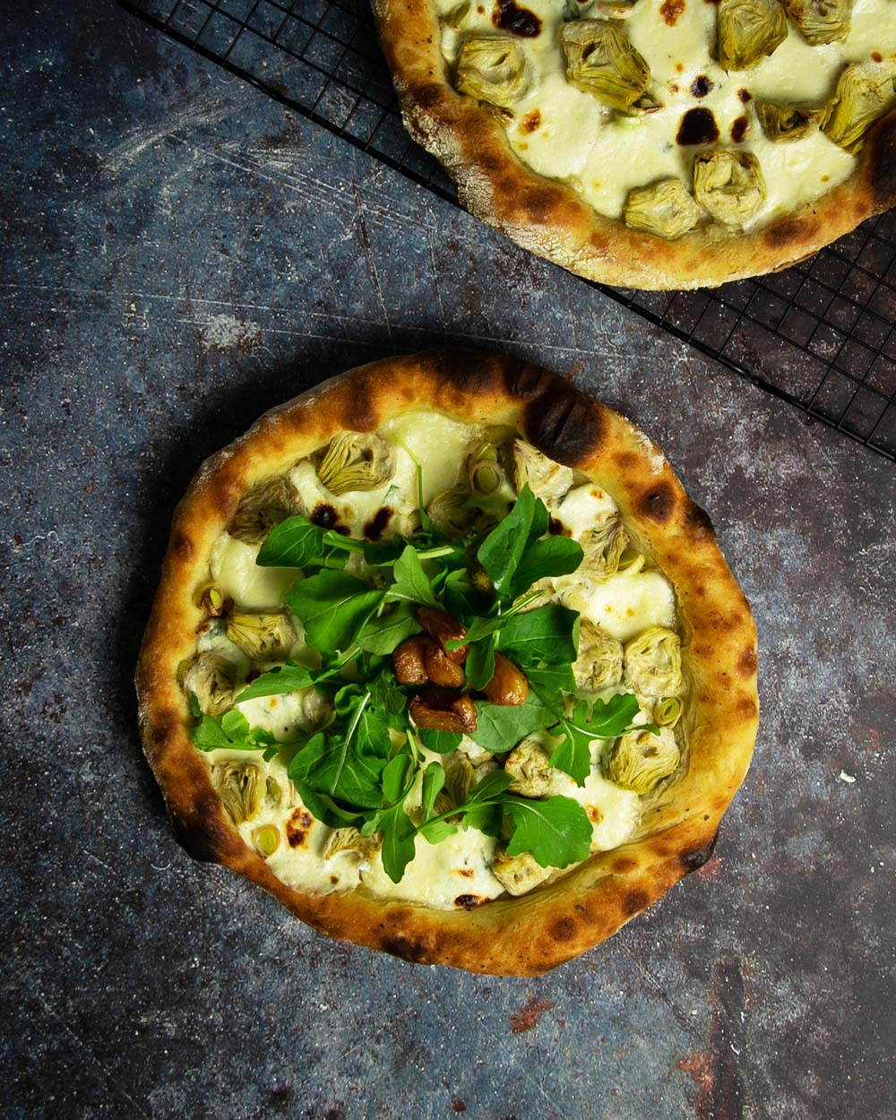 Top view of pizza bianca on a marbled surface topped with fresh arugula and garlic