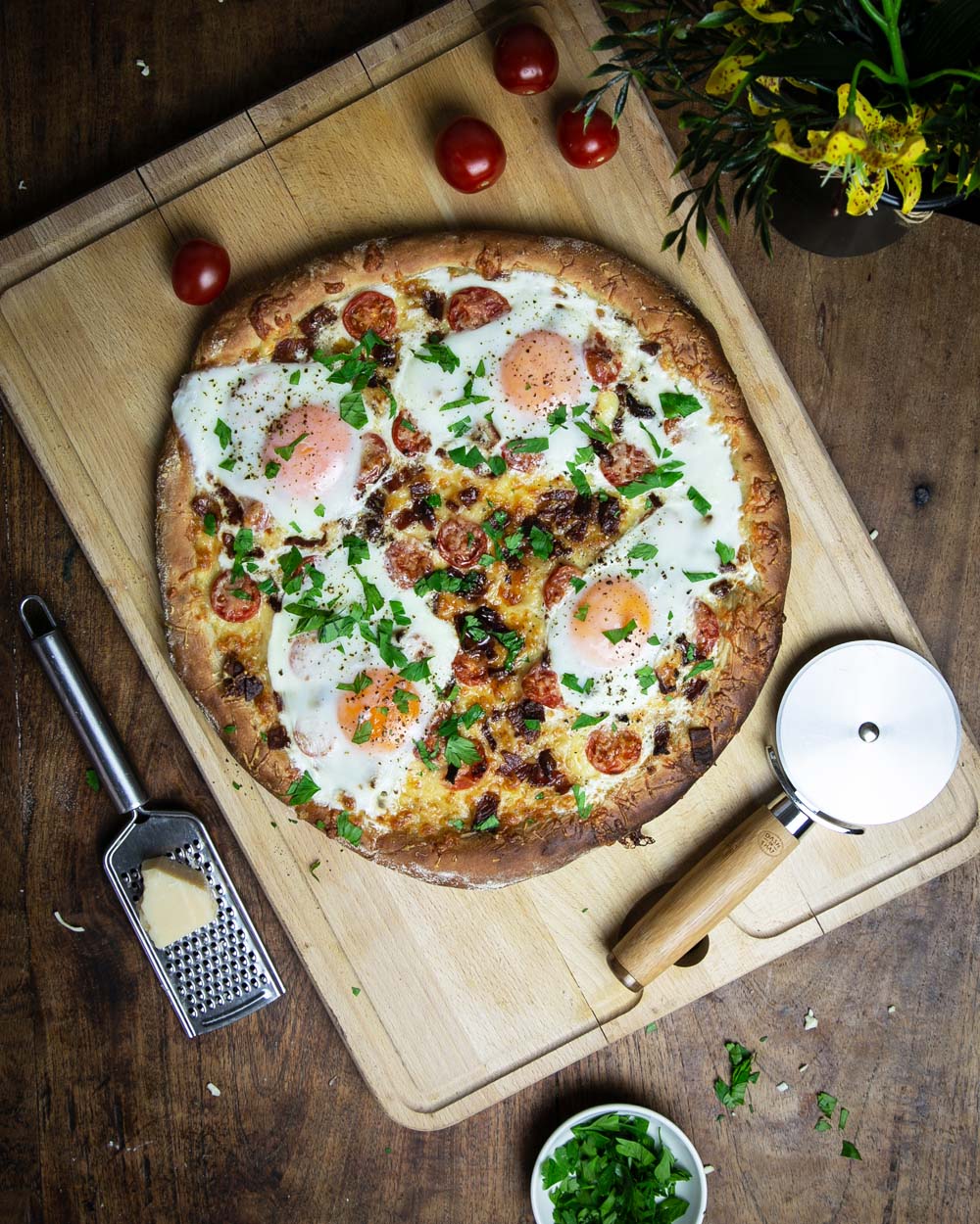 Top view of the classic breakfast pizza with sunny side up eggs on a wooden cutting board.