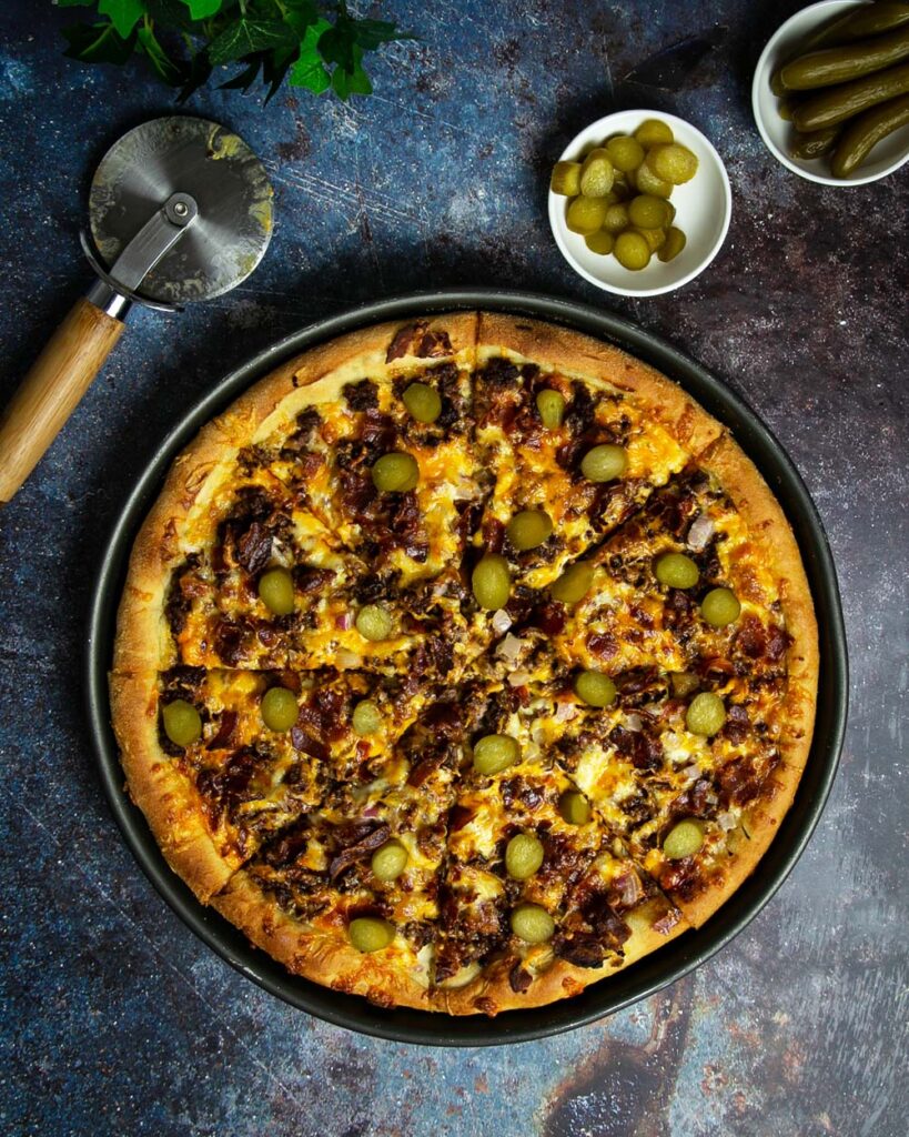 Top view of cheeseburger pizza on a marble background.