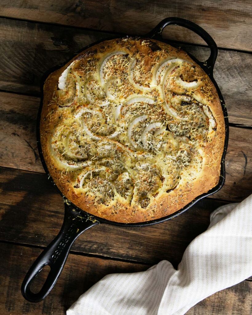 Argentinian fugazzeta in a cast iron skillet with a wood background