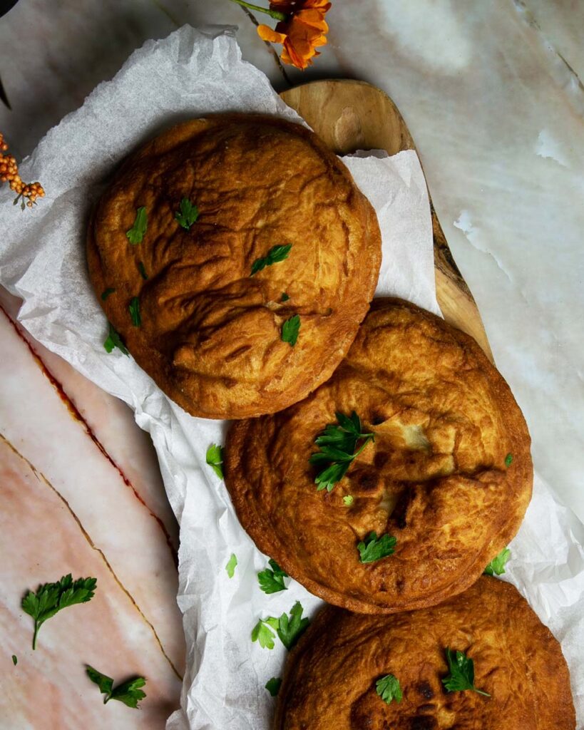 3 Italian pizza fritta on parchment sprinkled with parsley.