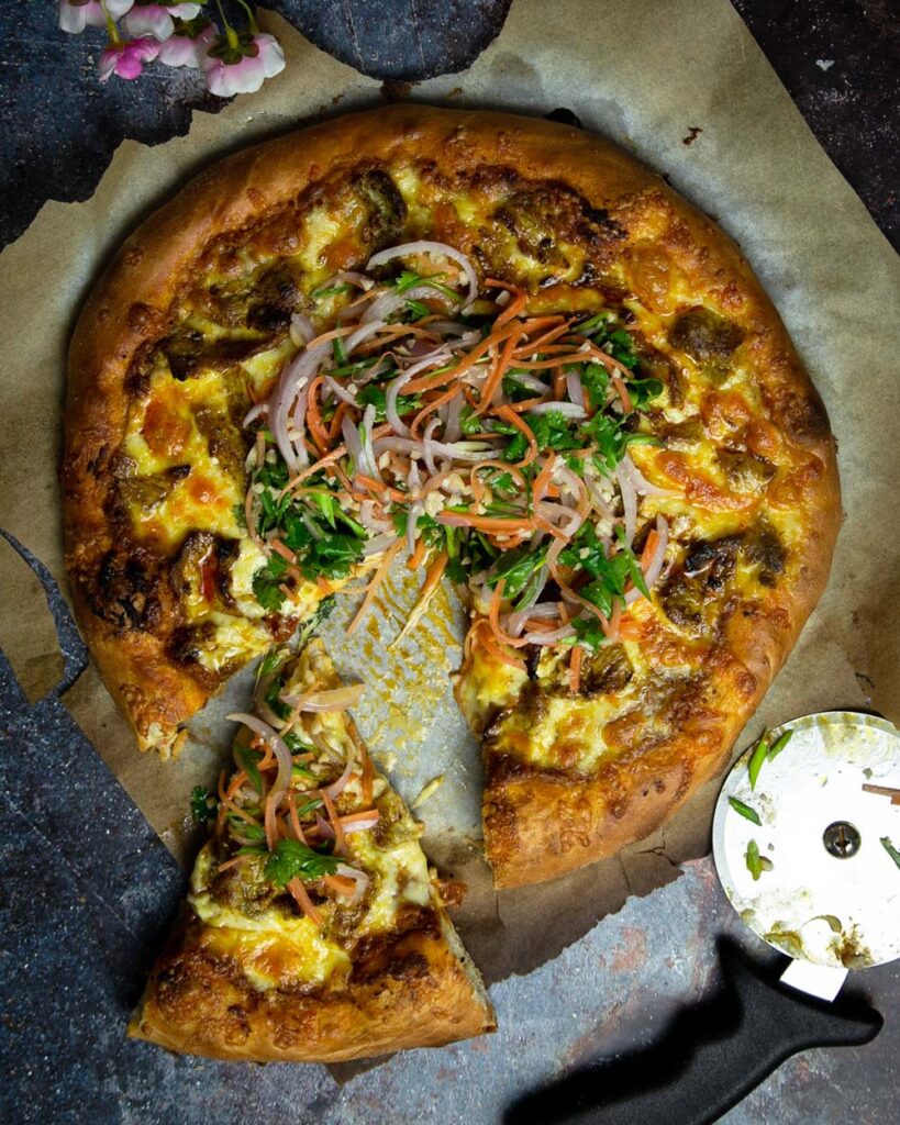 Thai satay pizza topped with a Thai salad, sliced and ready to eat.