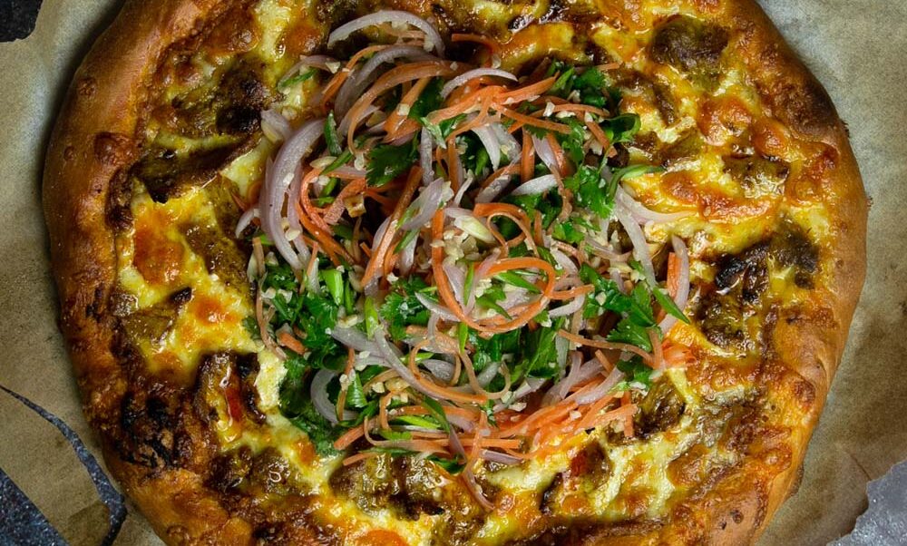 Top view of the Thai satay pizza on a dark marble background.