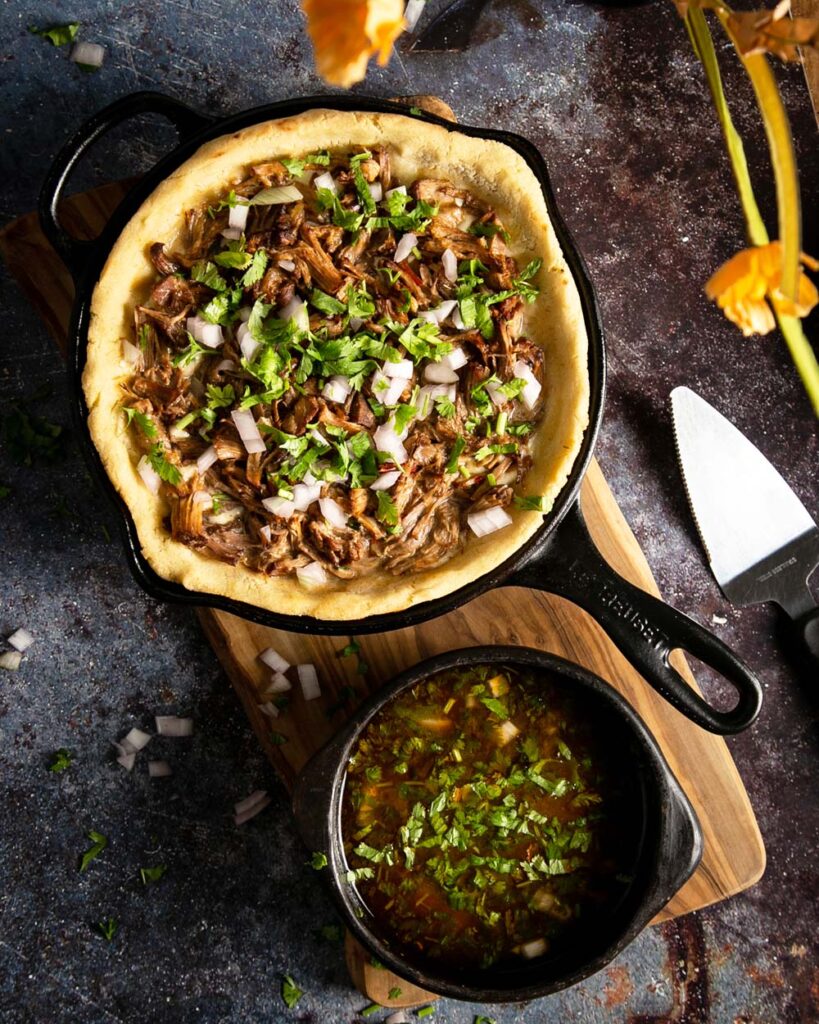 top view of birria pizza in a cast iron on a marble counter