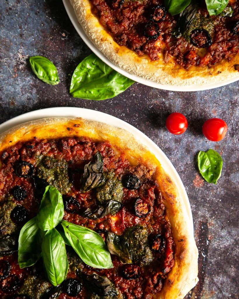 A pair of pesto Genovese pizza with sourdough crust, sprinkled with basil